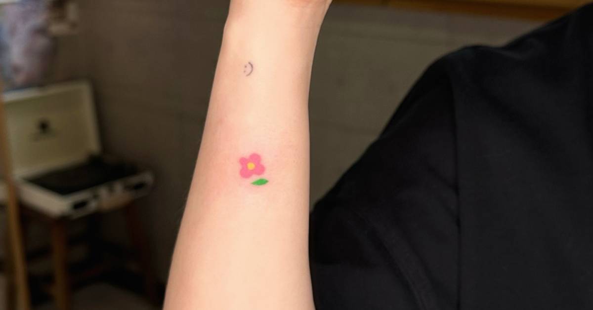 Minimalistic hand poked flower tattooed on the wrist.