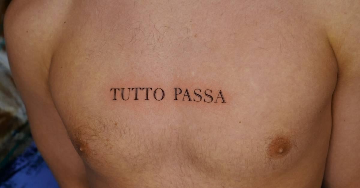 "Tutto passa" in serif font tattooed on the chest.