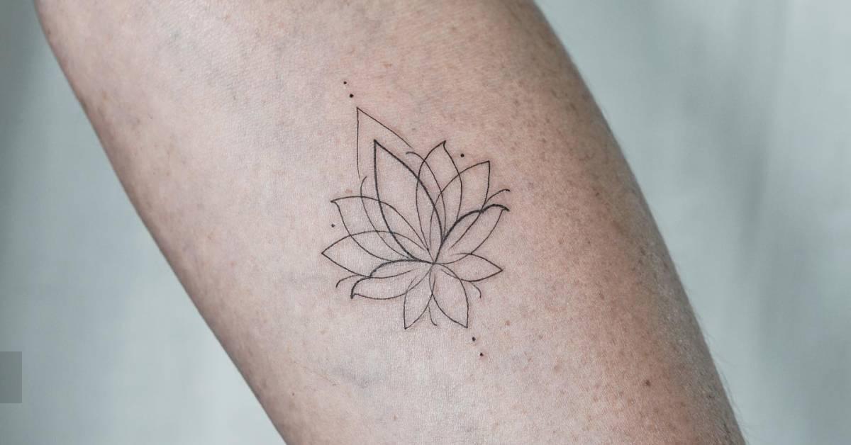 Little fine line lotus flower tattoo located on the