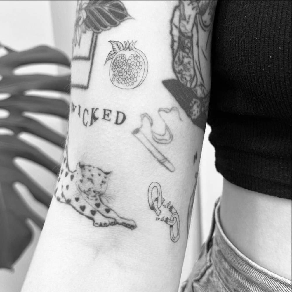 Fine line style pomegranate gap filler tattoo located on the bicep.