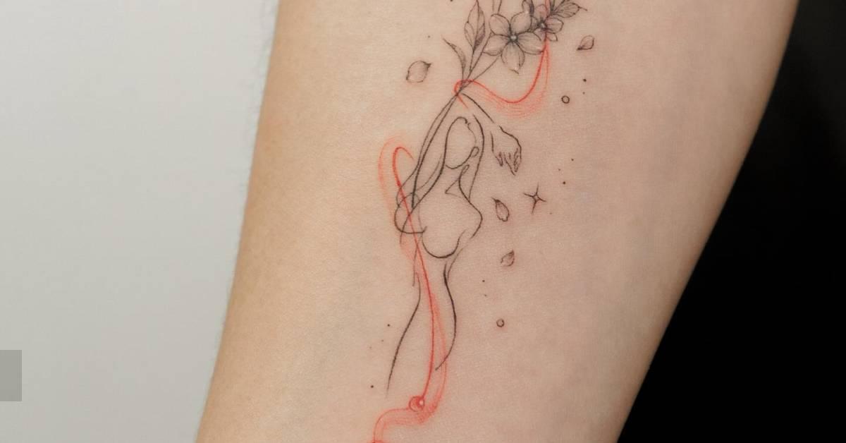 Flower head woman tattoo located on the inner forearm.