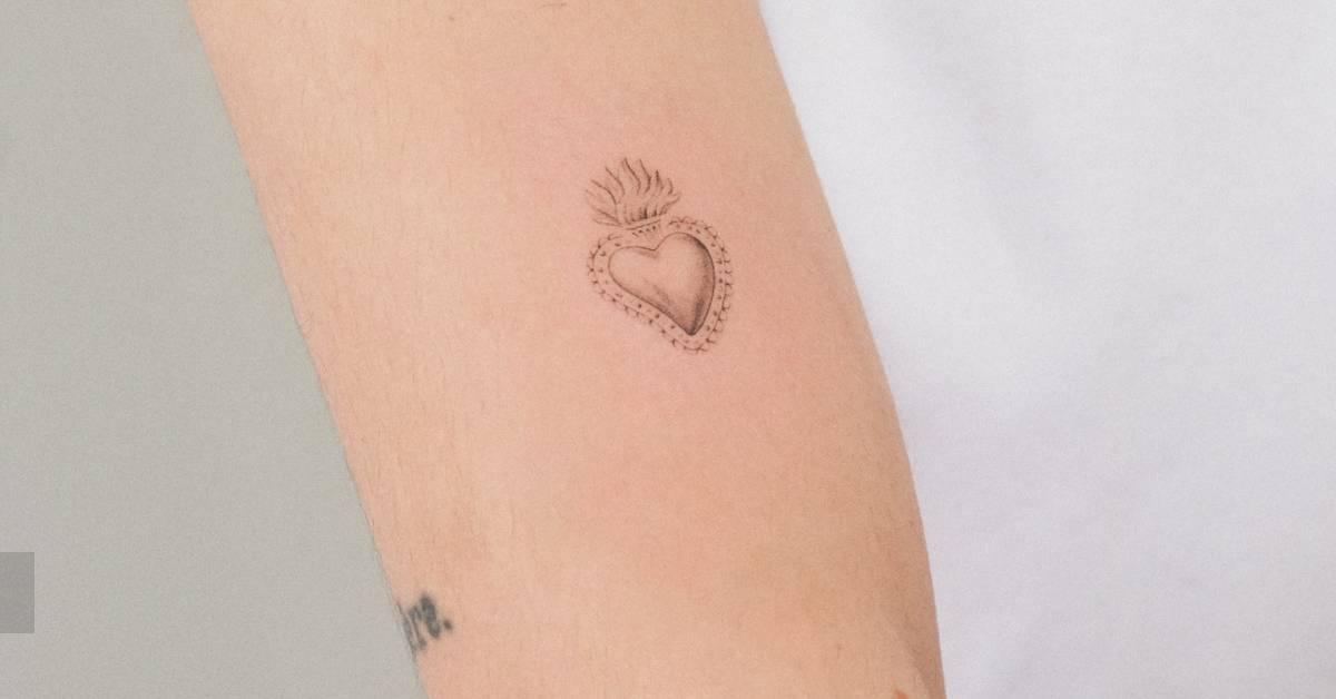 Single needle flaming heart tattoo located on the upper