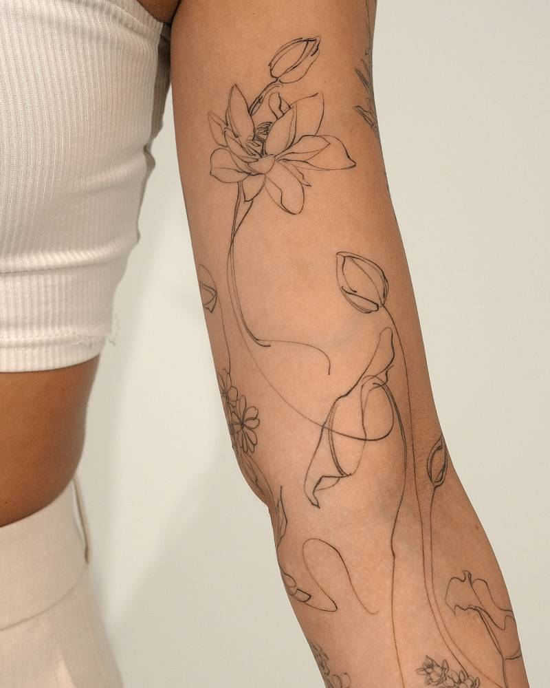Sketch work style lotus flower tattoo located on the arm.