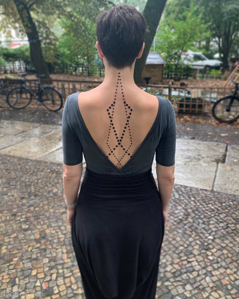 Dots tattoo in geometric style located on the upper back.