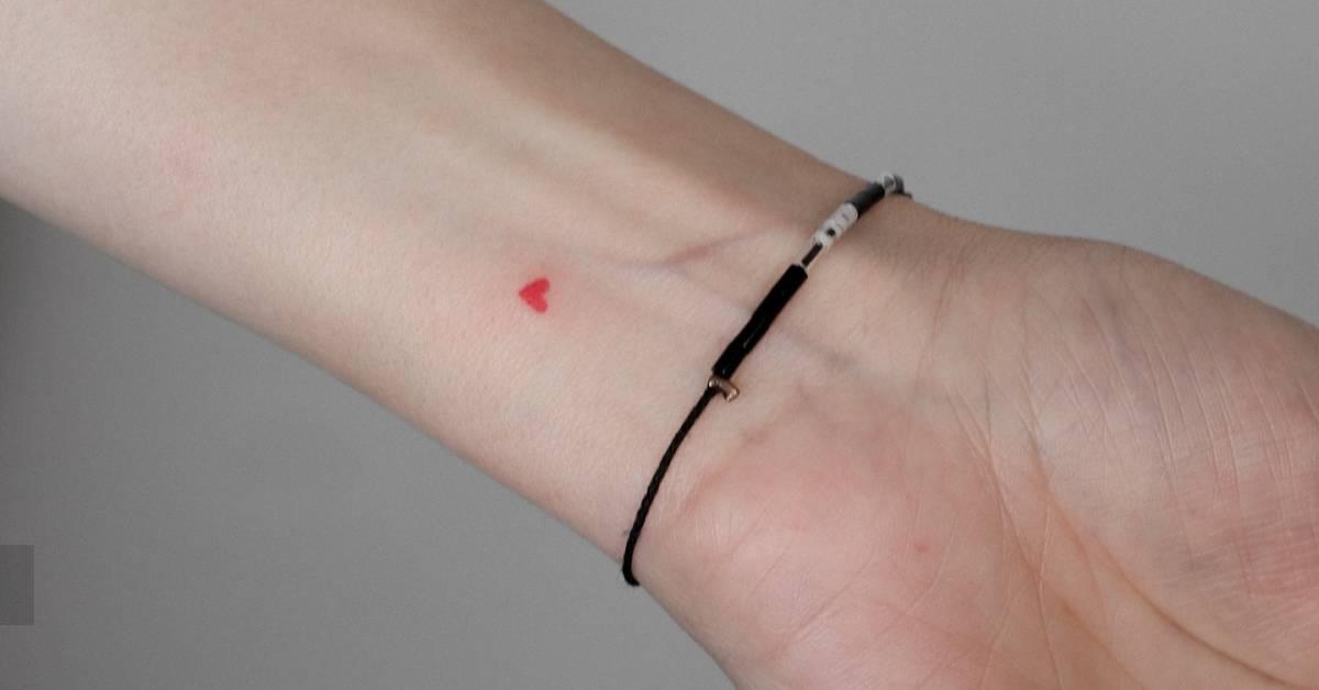 Tiny minimalistic red heart tattoo done on the wrist.