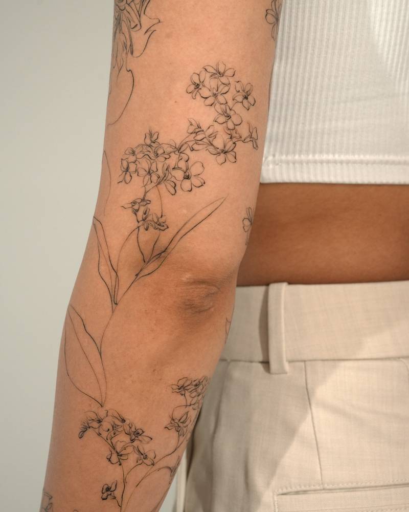 Sketch work style lilacs tattoo located on the arm.