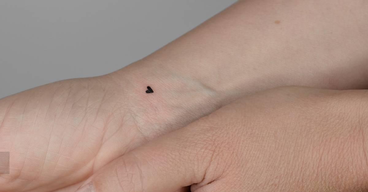 Tiny minimalistic heart tattoo located on the wrist.