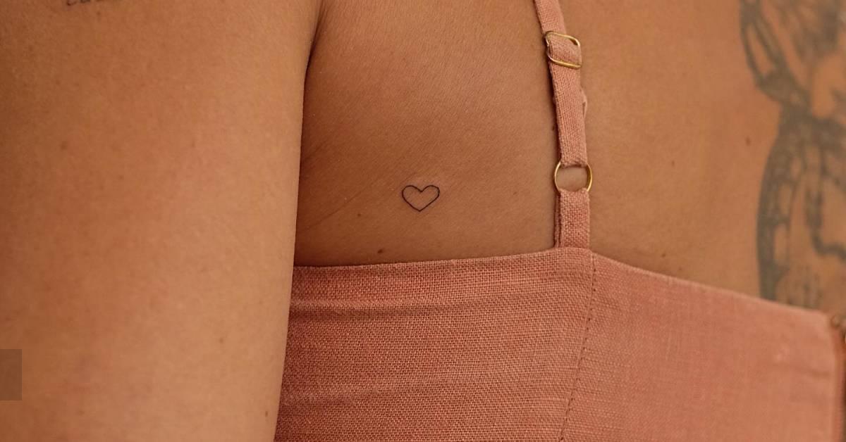 Tiny minimalistic heart tattoo located on the shoulder