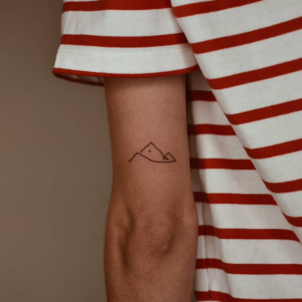 One line mountain tattoo located on the tricep.