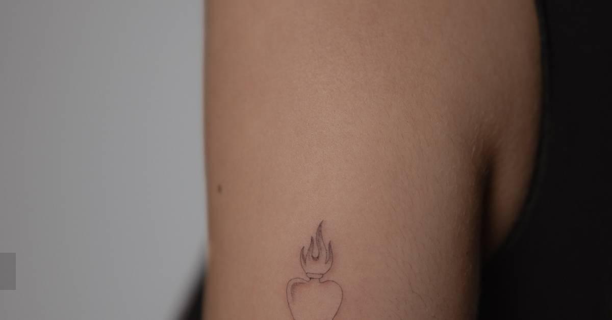 Single needle flaming heart tattoo located on the upper