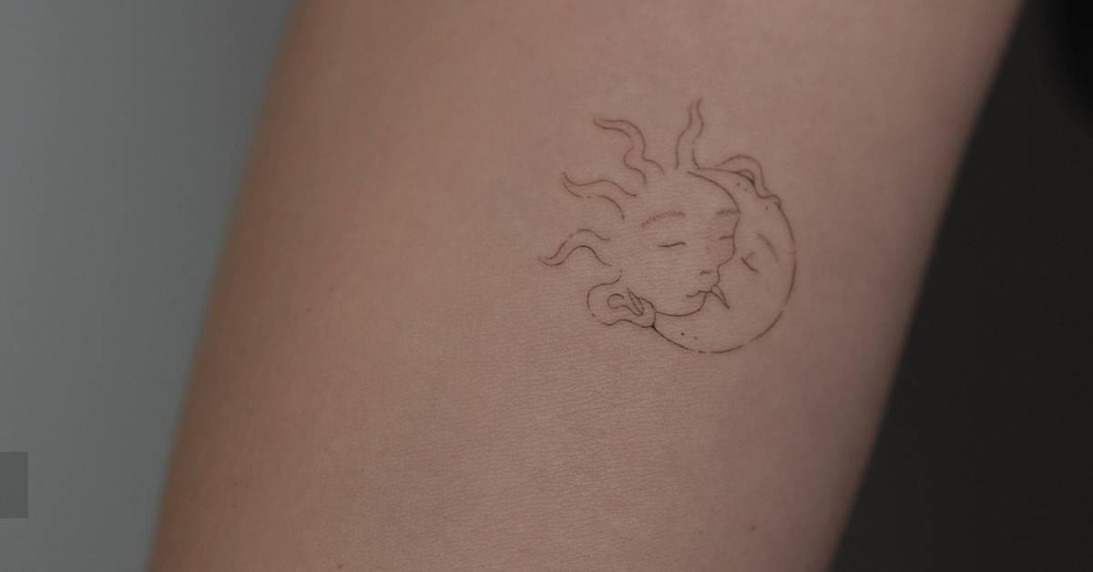Fine line style kissing sun and moon tattoo located on