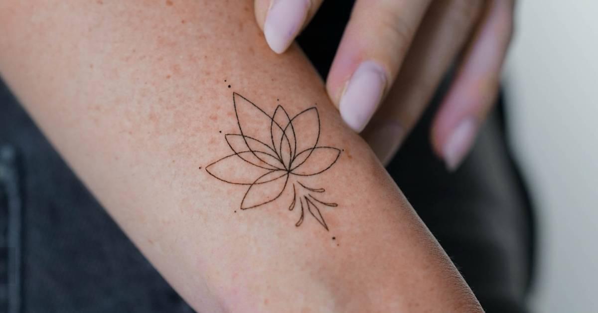 Fine line style lotus flower tattoo located on the