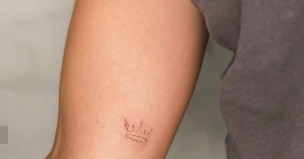Fine line style crown tattoo located on the inner arm.