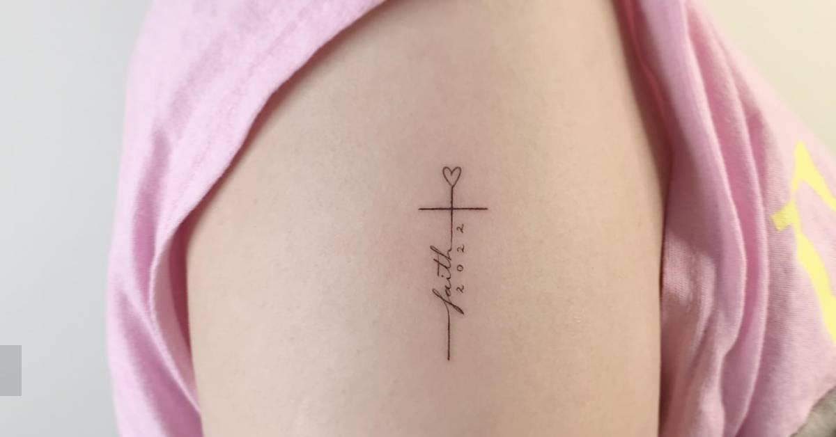 Minimalistic style faith cross tattoo located on the
