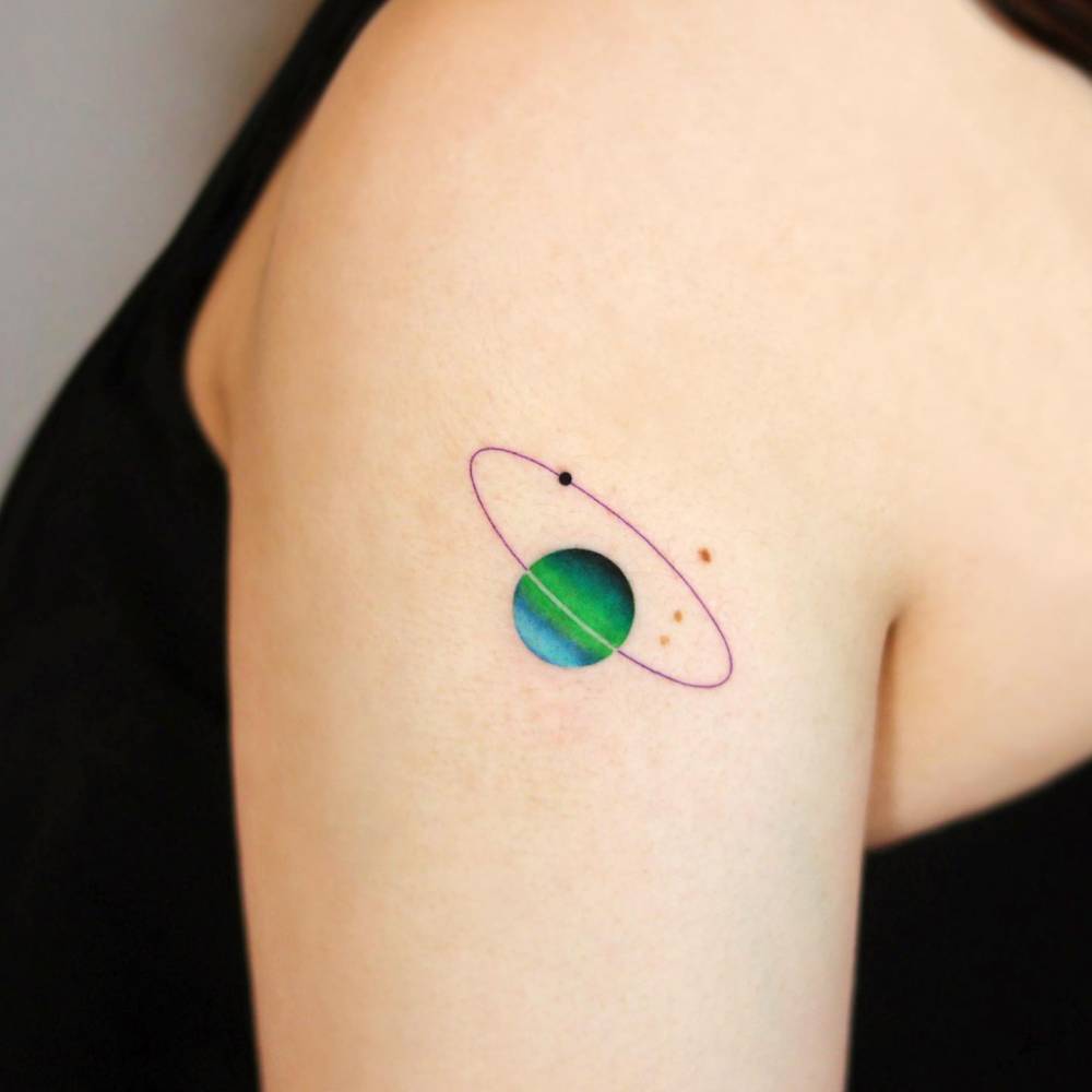Watercolor style Saturn tattoo located on the upper arm.