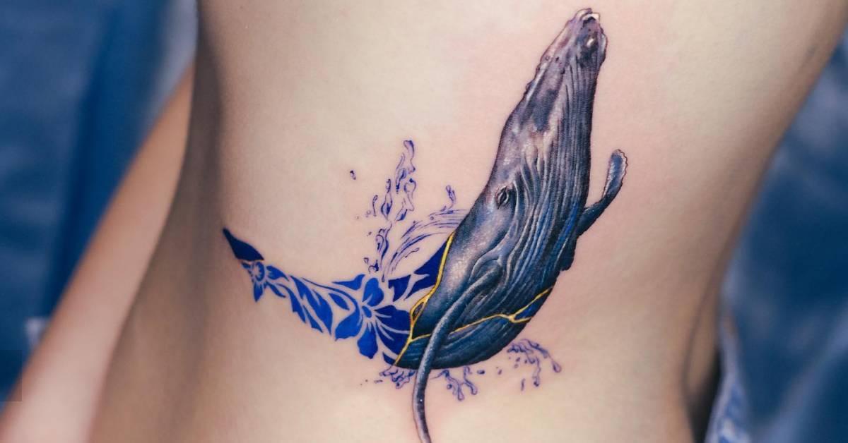 Contemporary style whale tattoo located on the rib.