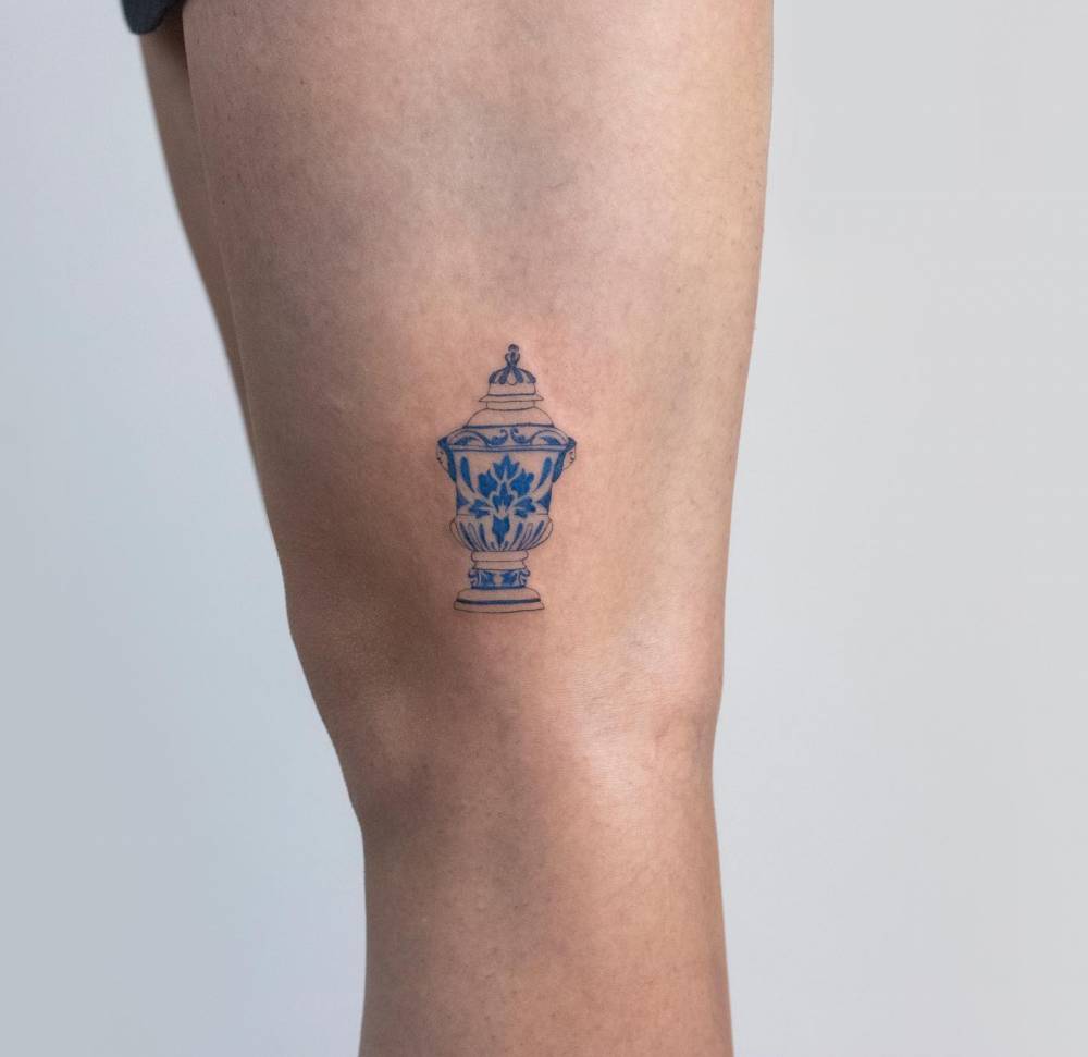 Porcelain vase tattoo located on the thigh.