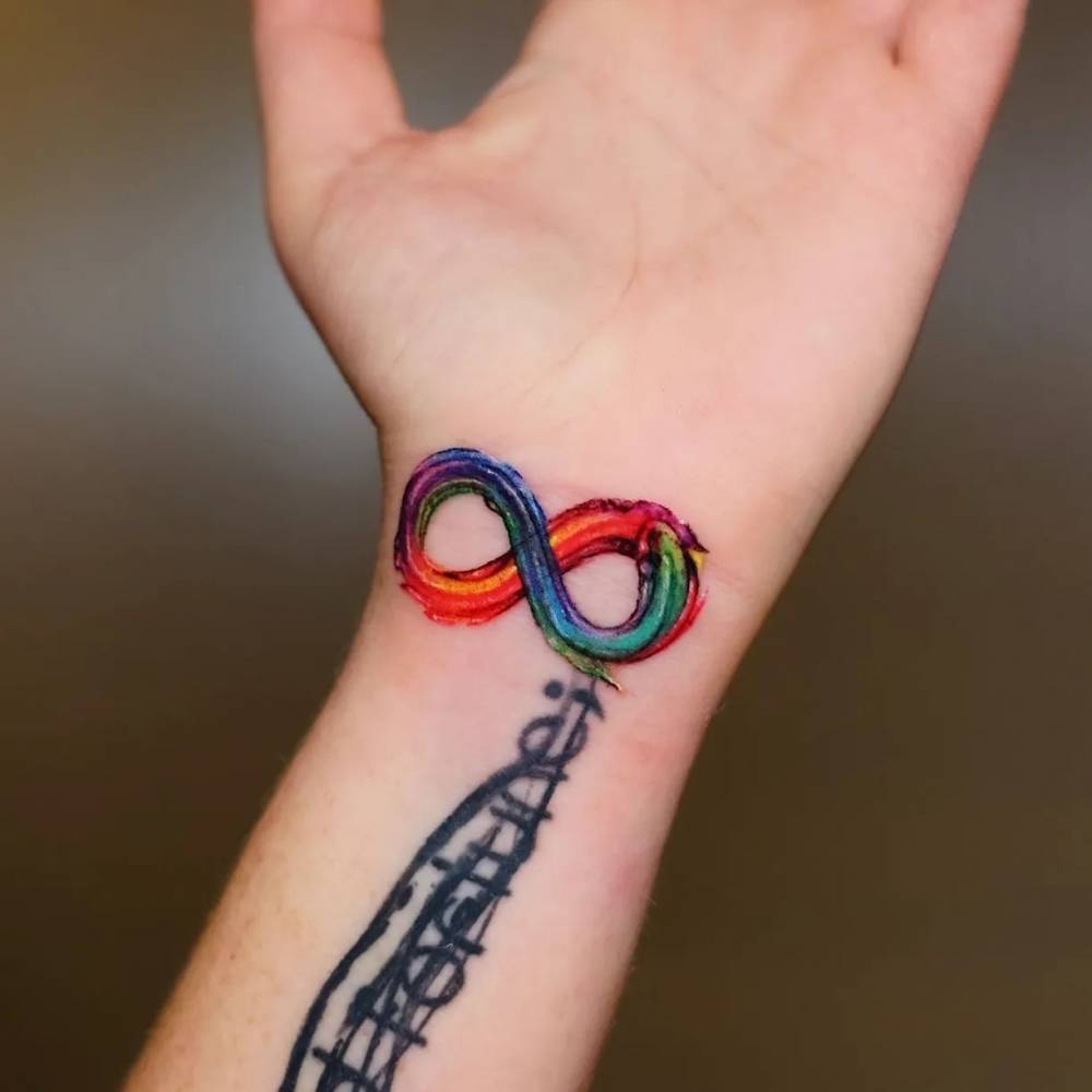 Watercolor style infinity symbol tattoo done on the wrist.