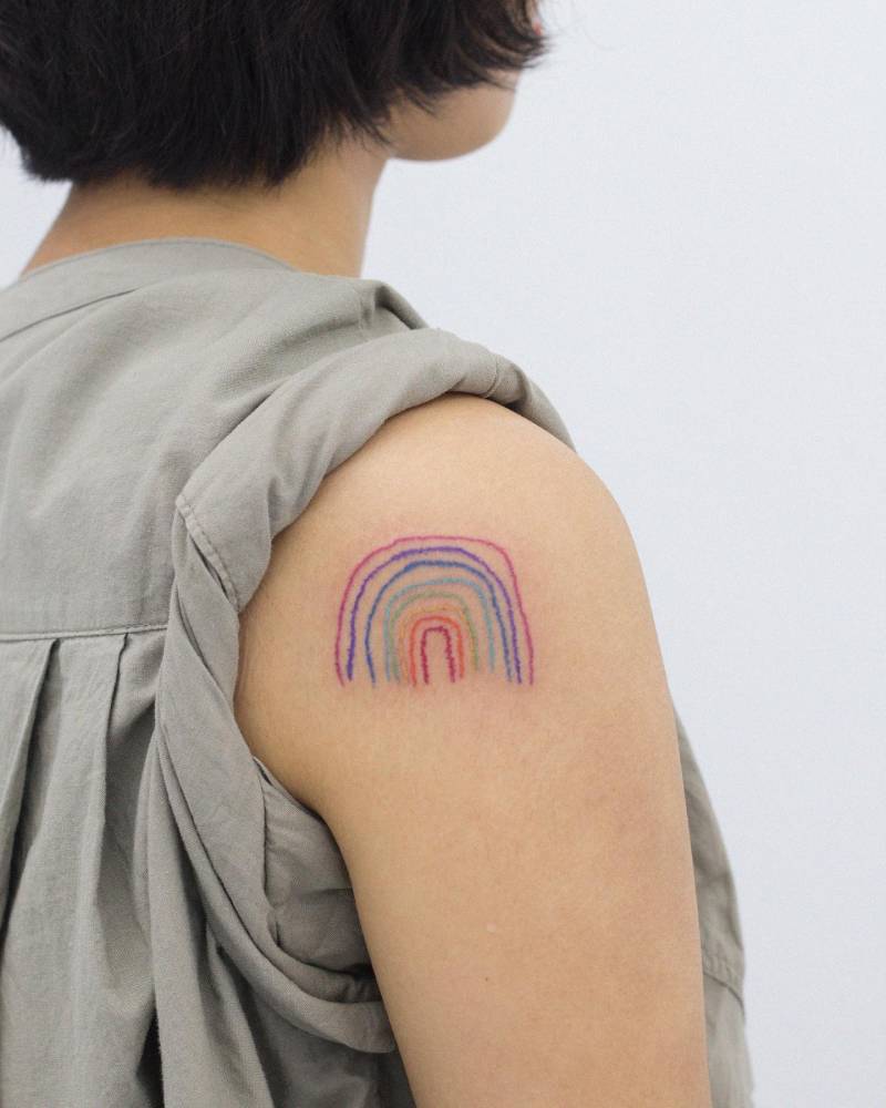 Watercolor style rainbow tattoo done on the shoulder.