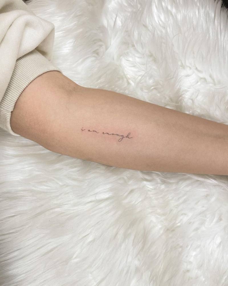 Tattoo that says "I am enough" handwritten on the inner forearm.