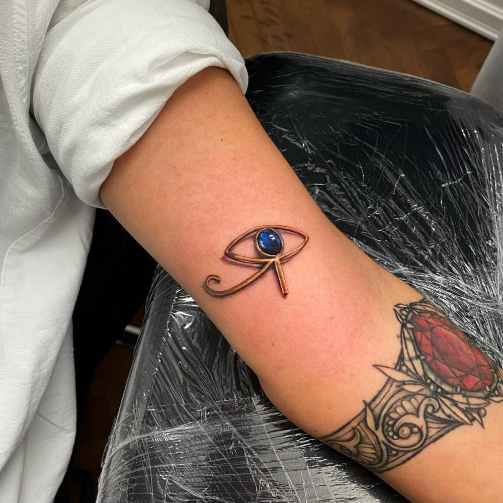 Eye of Ra tattoo located on the tricep, micro-realistic style.