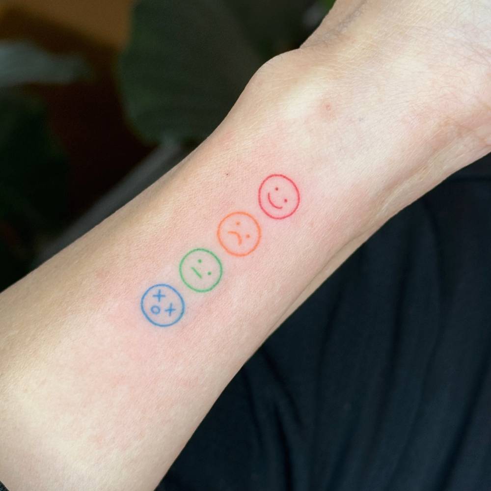 Emojis tattoo in minimalistic style hand poked on the wrist.