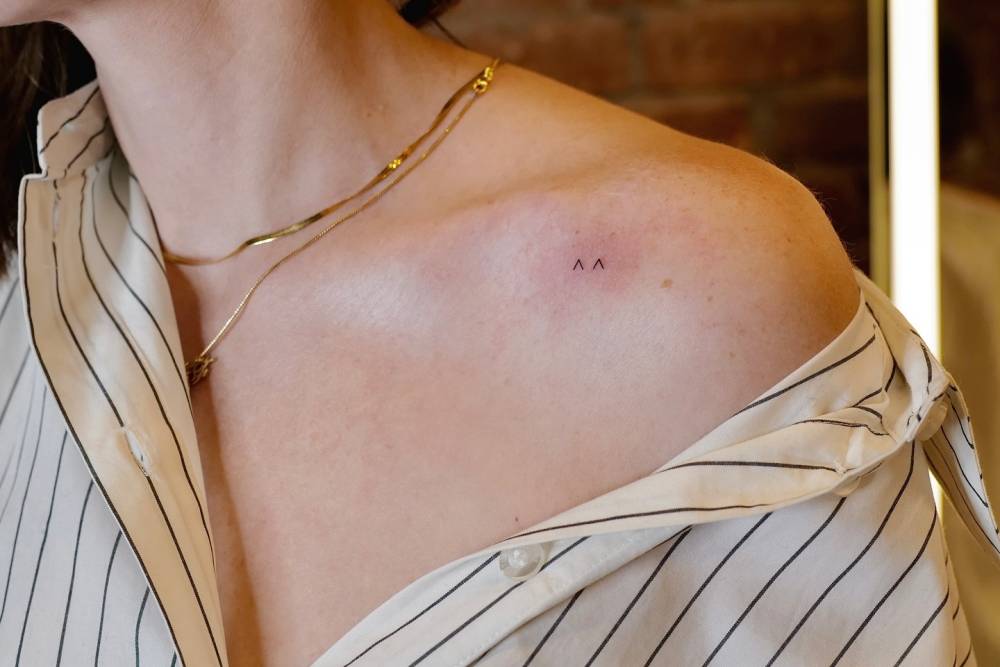 Minimalistic style circumflex eyes tattooed on the collarbone.