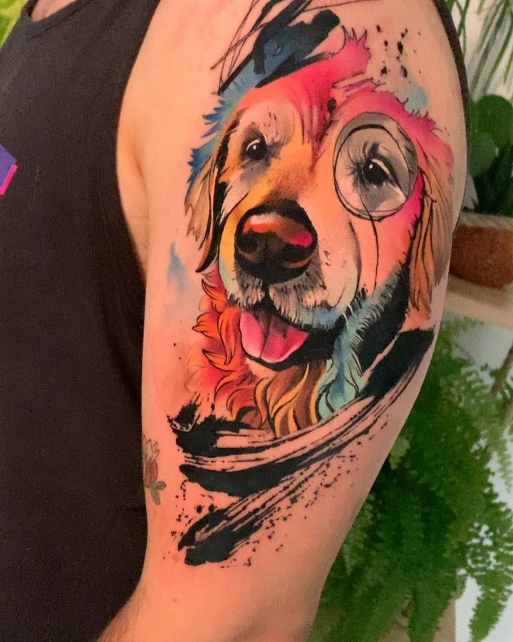 Watercolor style golden retriever portrait tattoo on the upper arm.