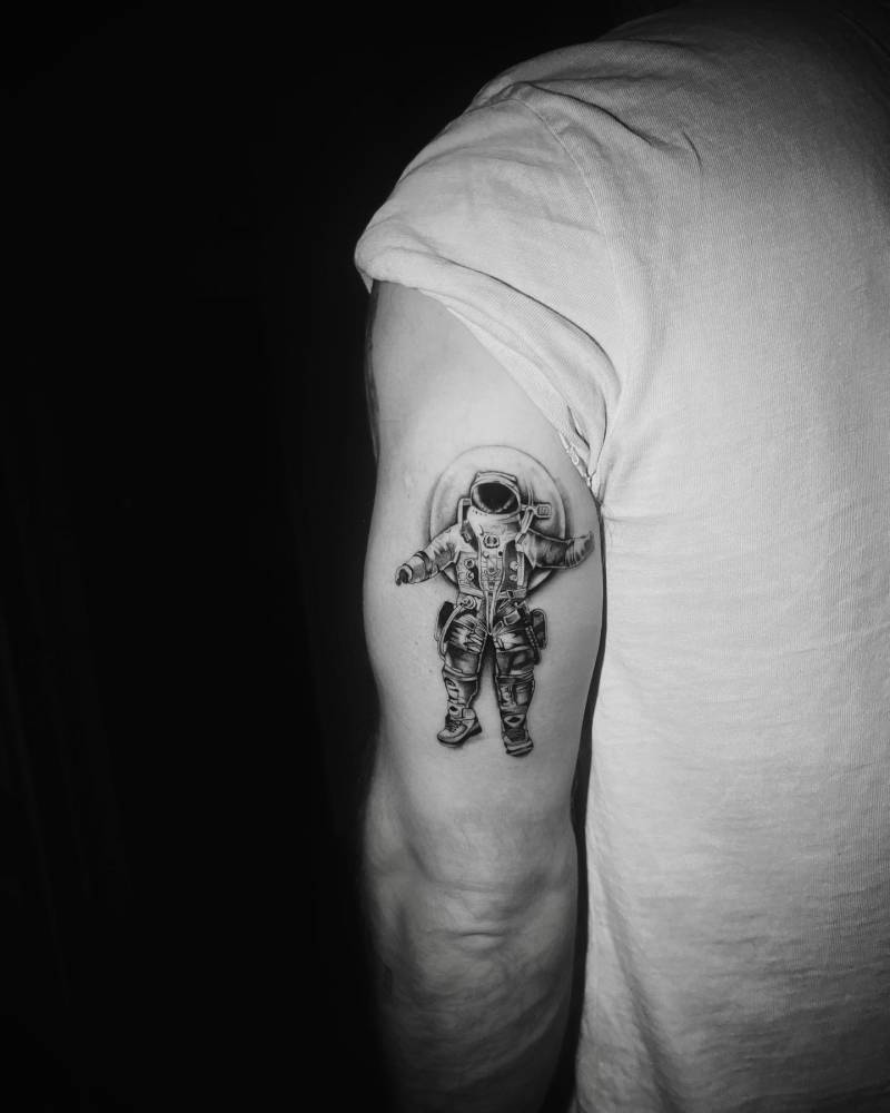 Astronaut tattoo located on the tricep, black and grey style.