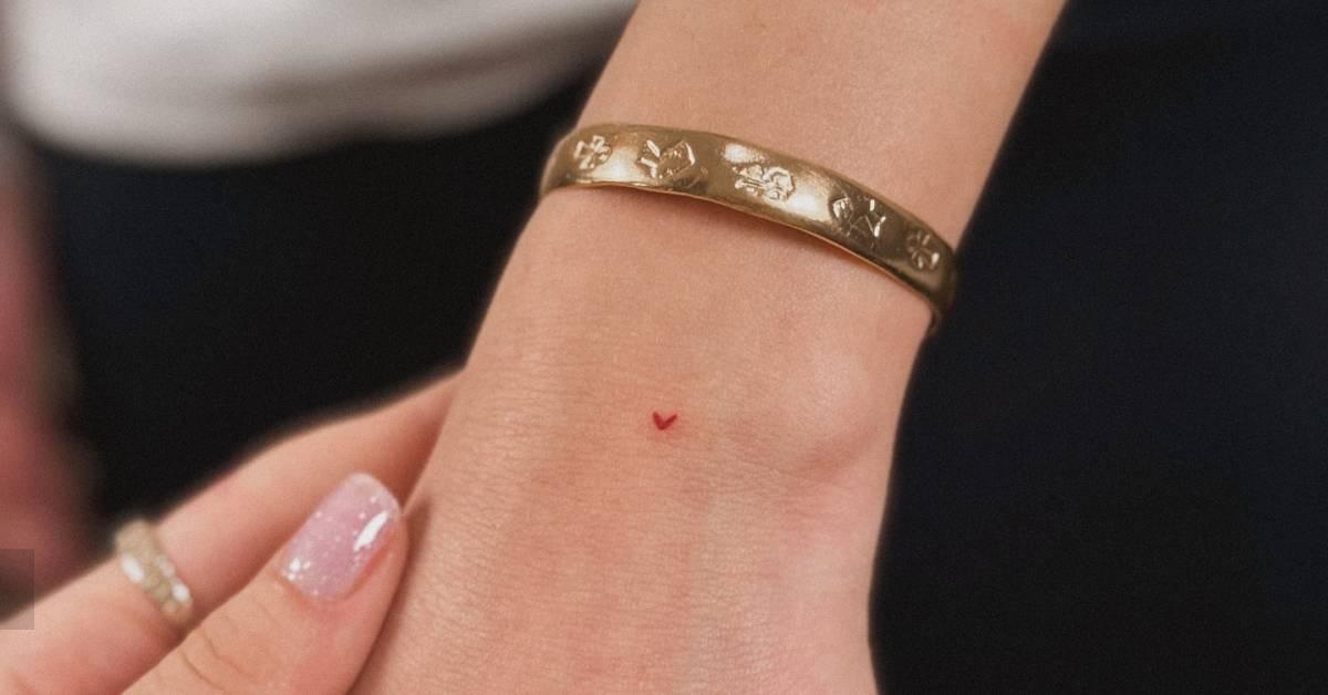Tiny minimalistic red heart tattoo placed on the wrist.