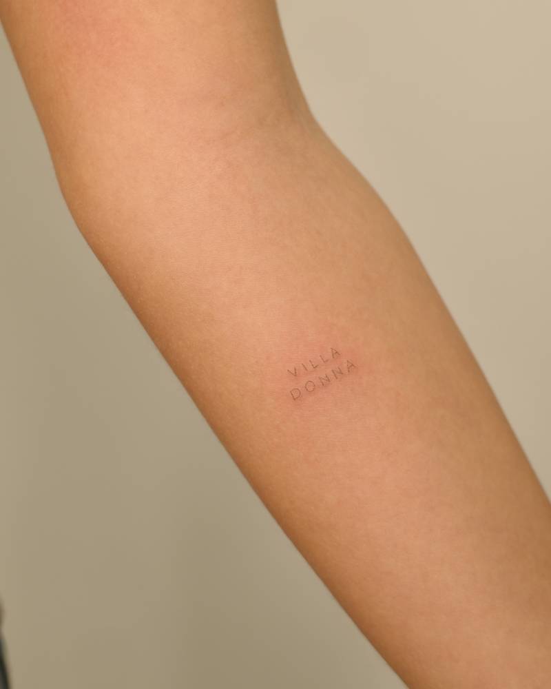 "Villa Donna" lettering tattoo located on the inner forearm.