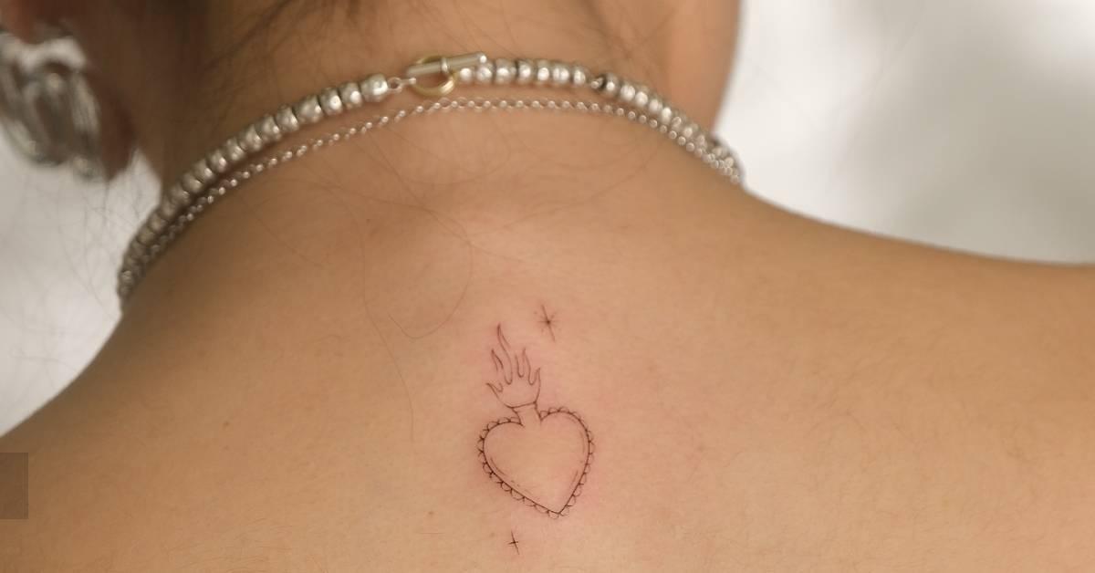 Fine line style flaming heart tattoo located on the