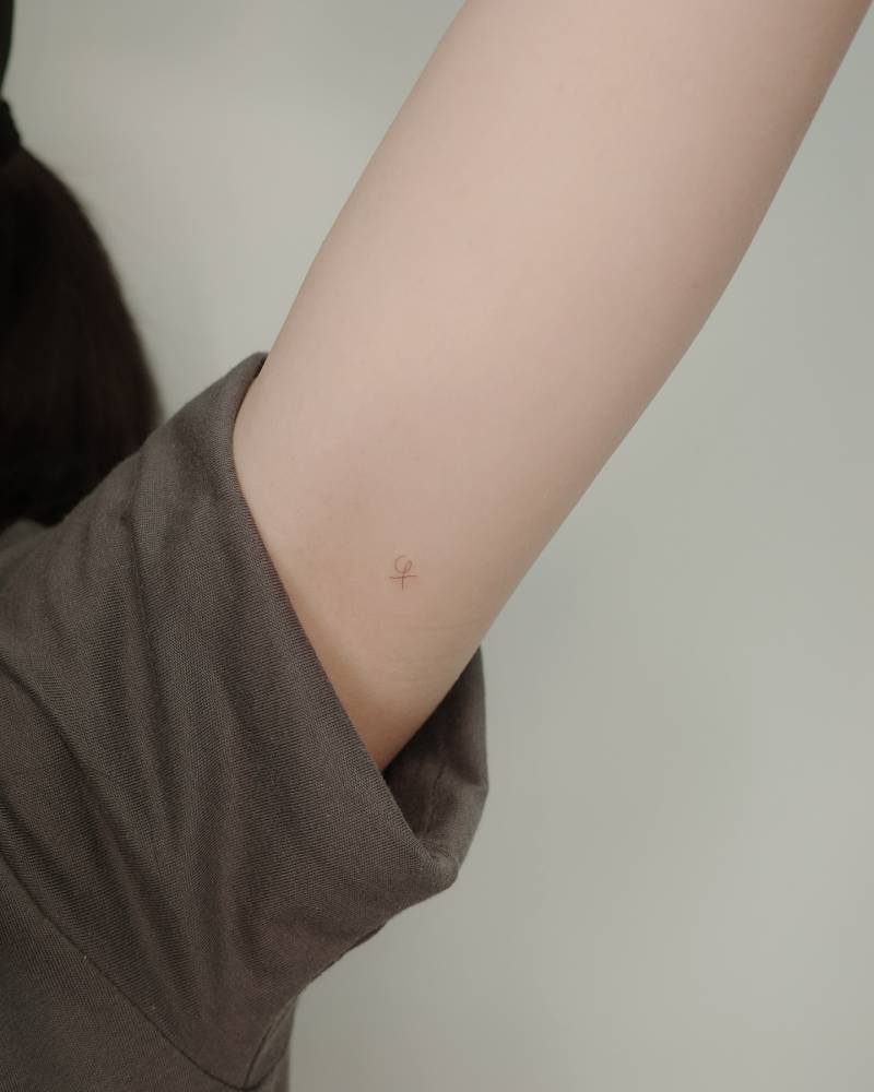 Tiny minimalistic symbol tattoo placed on the inner forearm.
