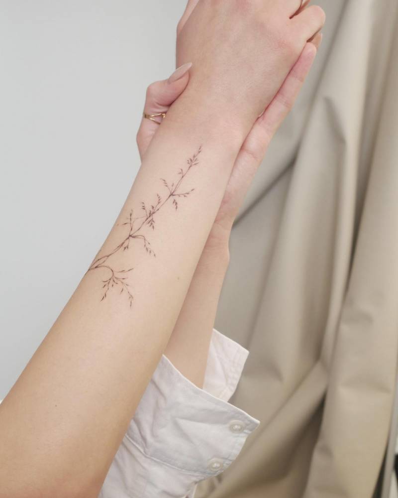 Grass tattoo located on the wrist, illustrative style.