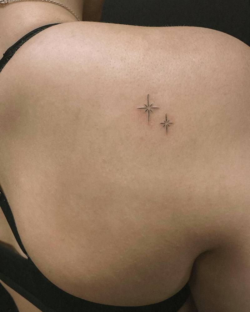 Sparkling stars tattoo in minimalistic style done on the shoulder blade.