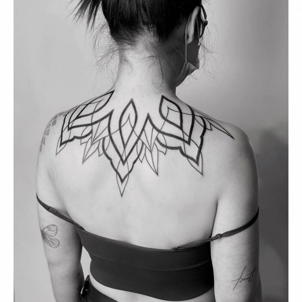 Line art lotus flower tattoo located on the upper back.