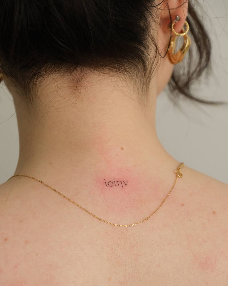 Little Greek lettering tattoo located on the upper back.