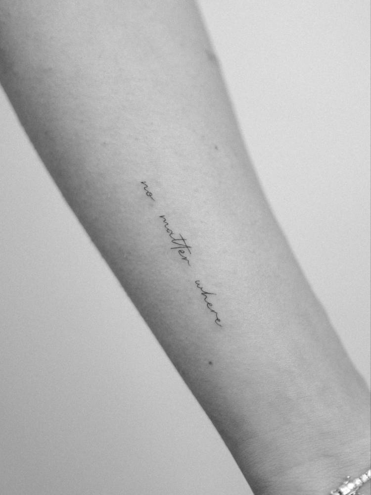 Handwritten lettering tattoo that says "no matter where" located on the wrist.