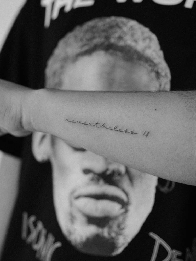 Lettering tattoo of the word "nevertheless" handwritten on the wrist.