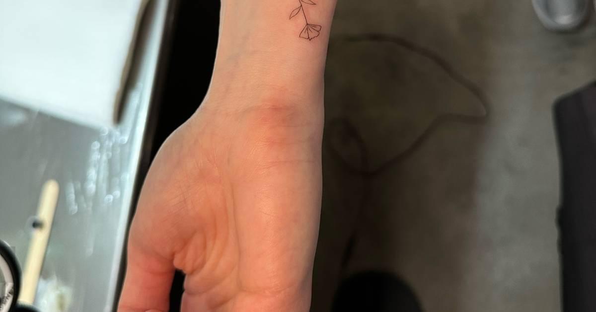 Tiny fine line style flower tattoo located on the
