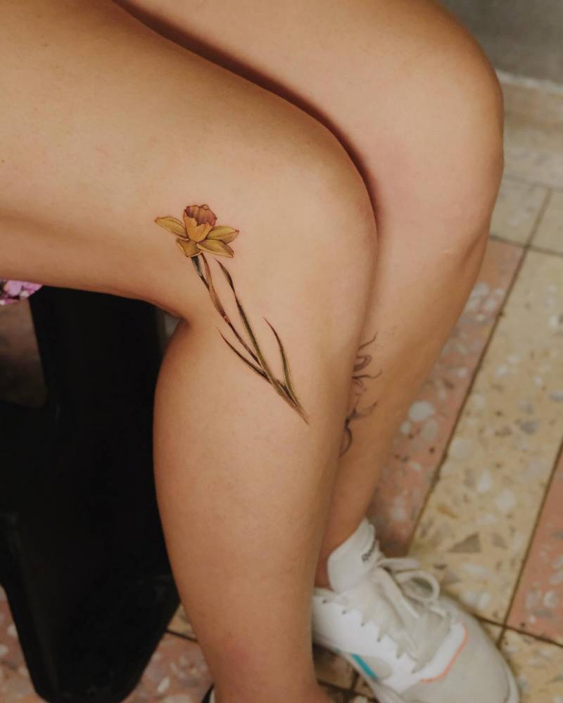 Watercolor style daffodil tattoo located on the knee.