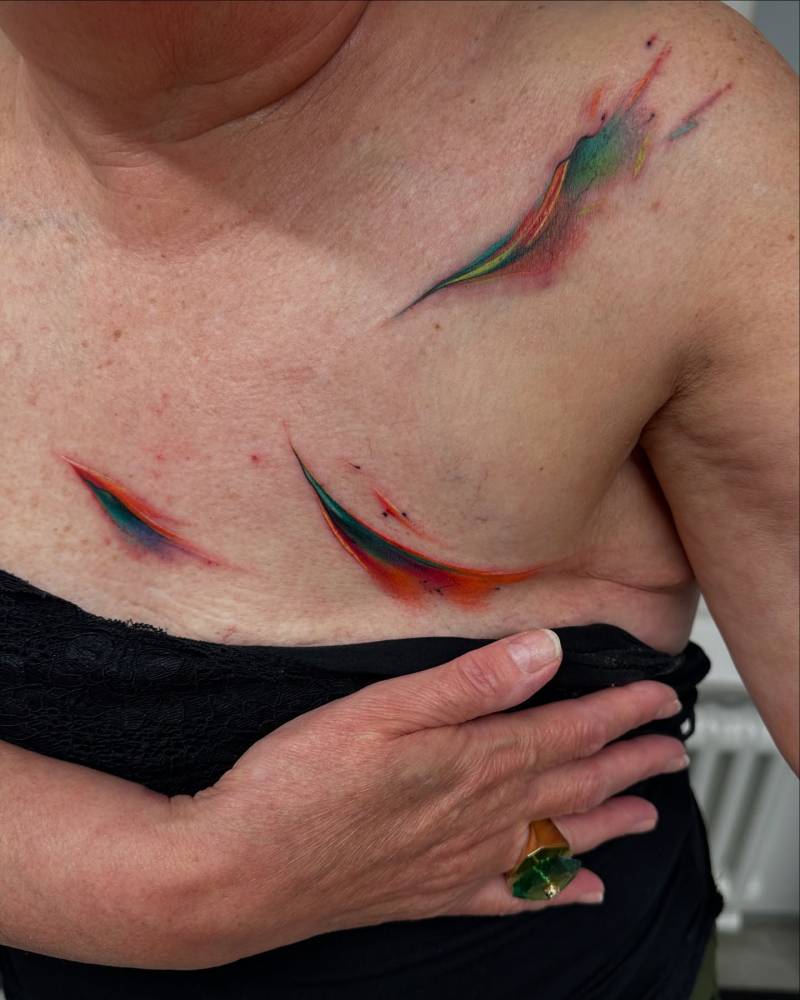 Abstract watercolor tattoo located on the chest and shoulder.
