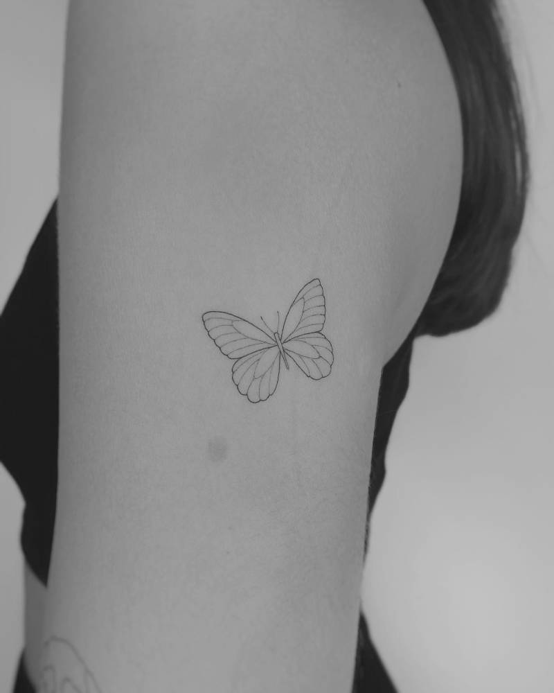Butterfly tattoo located on the upper arm, fine line style.