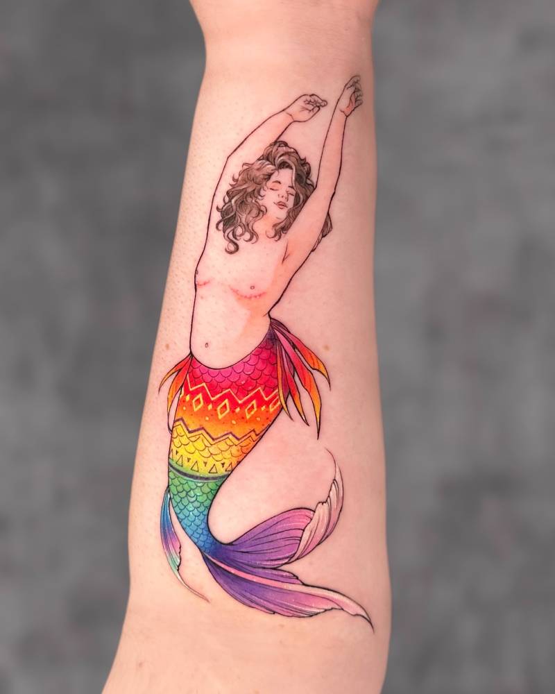 Rainbow mermaid tattooed on the inner forearm, watercolor style.