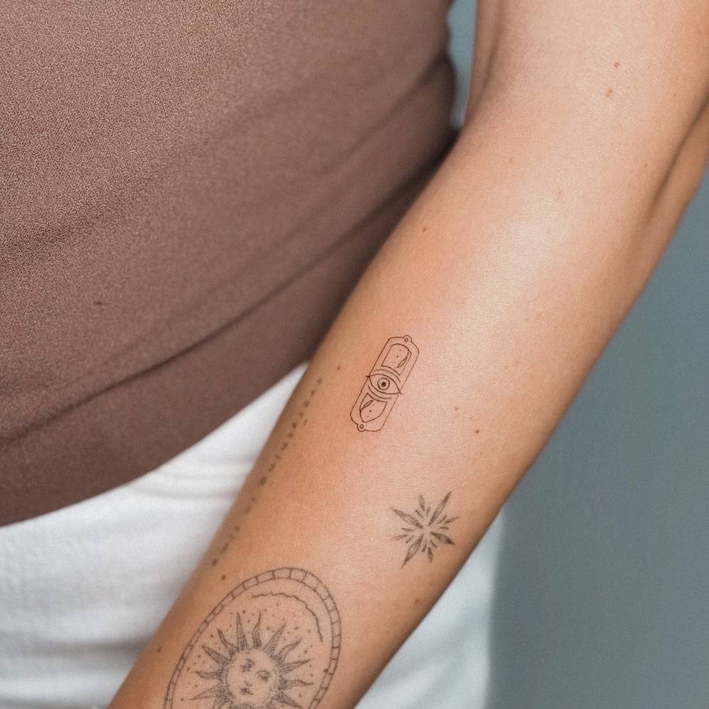 Ornamental eye tattoo in fine line style located on the forearm.