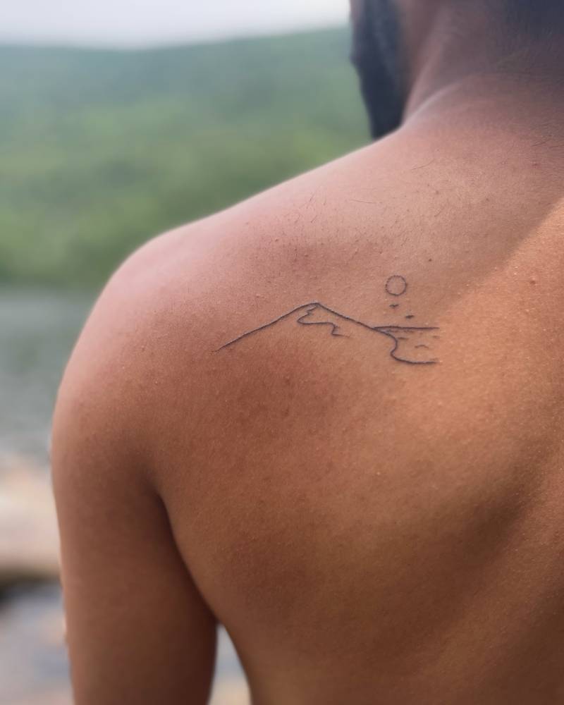 Hand poked minimalistic mountain and sea tattoo located on the shoulder blade.