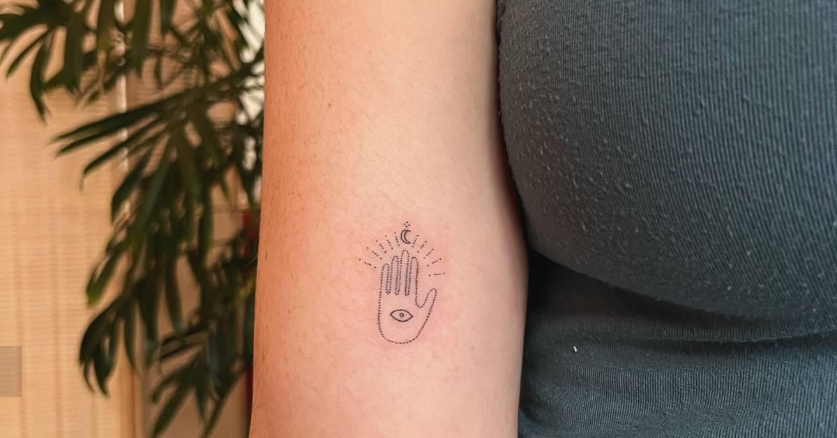 Hand poked minimalistic hand and eye tattoo located on