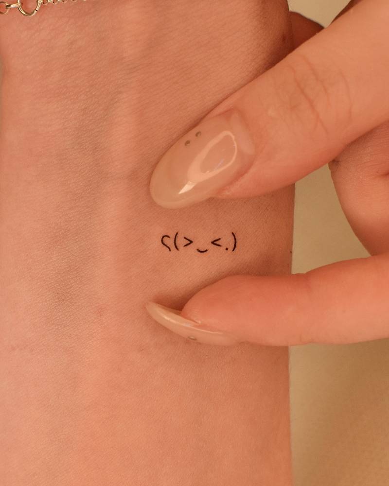 Tiny minimalistic emoji face tattooed on the wrist.