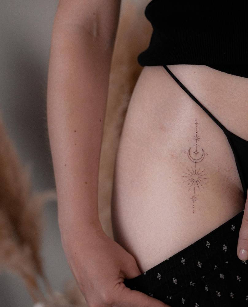Ornamental sun and moon tattoo located on the pelvis.