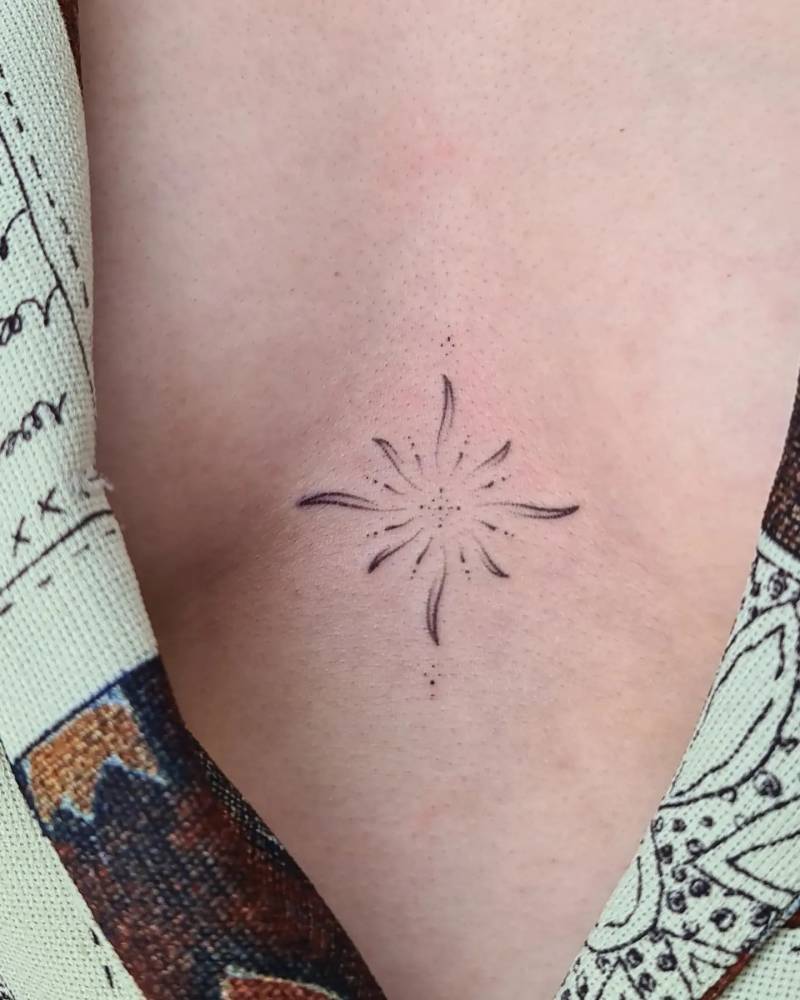 Hand poked abstract sun tattoo located on the sternum.